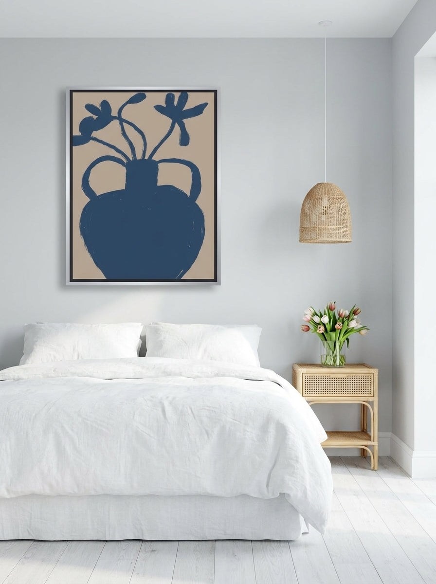 Canvas wall art with a silver leaf surround styled on the wall in a bright Scandinavian bedroom