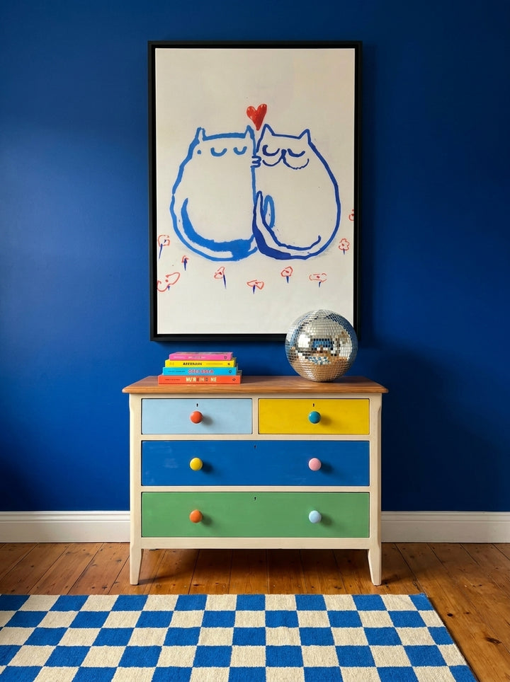 Canvas wall art with a black surround styled on the wall in a colourful eclectic nursery