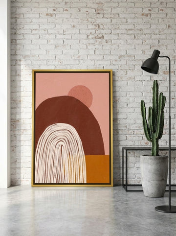 Canvas wall art with a gold leaf surround leaning against the wall in an industrial loft home office