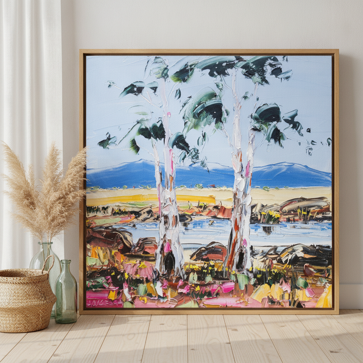 Oversized statement canvas wall art with a natural timber surround leaning against the wall in a coastal dining room