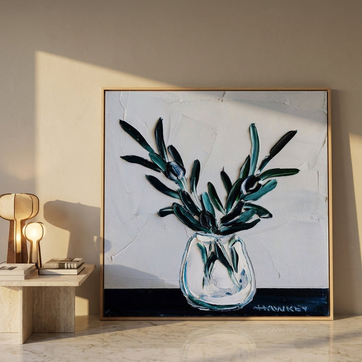 Oversized statement canvas wall art with a natural timber surround leaning against the wall in a luxe dining room