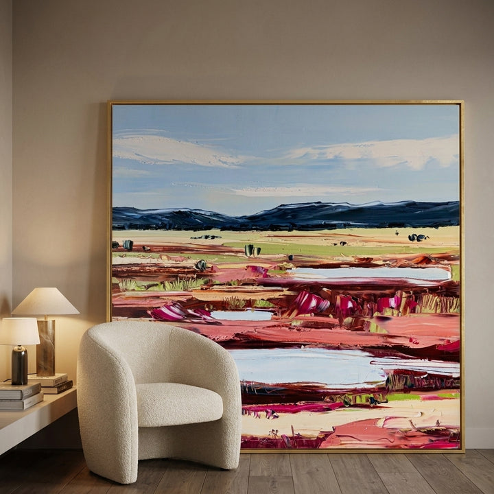 Oversized statement canvas wall art with a gold leaf surround leaning against the wall in a luxe dining room