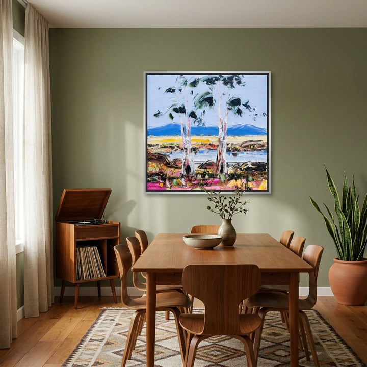 Canvas wall art with a silver leaf surround styled on the wall in a mid-century dining room