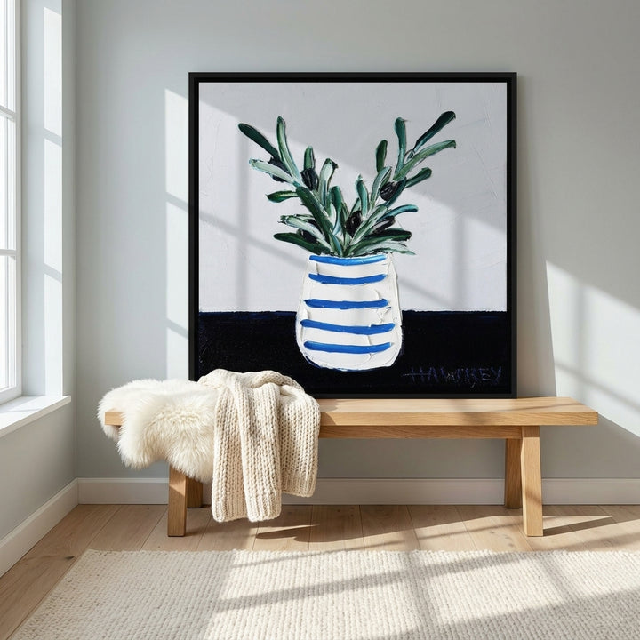 Canvas wall art with a black surround standing on a bench in a bright Scandinavian living room