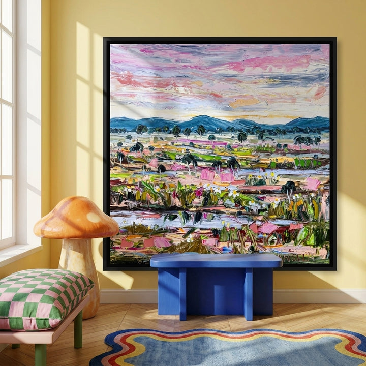 Canvas wall art with a black surround standing on a side table in a colourful eclectic bedroom