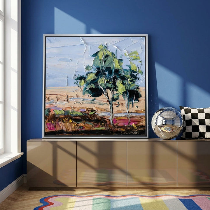 Canvas wall art with a silver leaf surround standing on a sideboard in a colourful eclectic home office