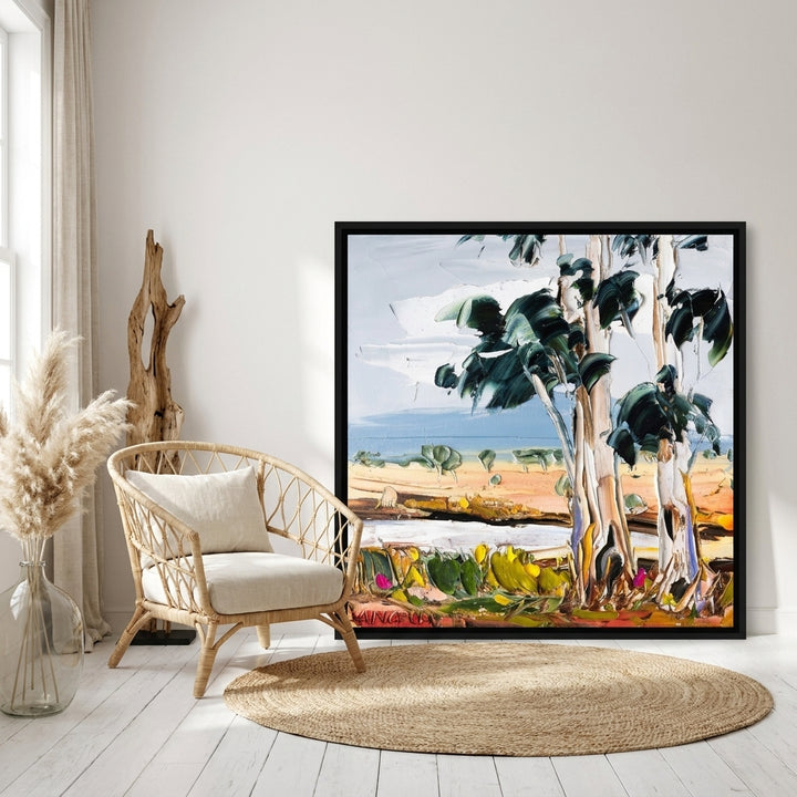 Oversized statement canvas wall art with a black surround leaning against the wall in a coastal dining room