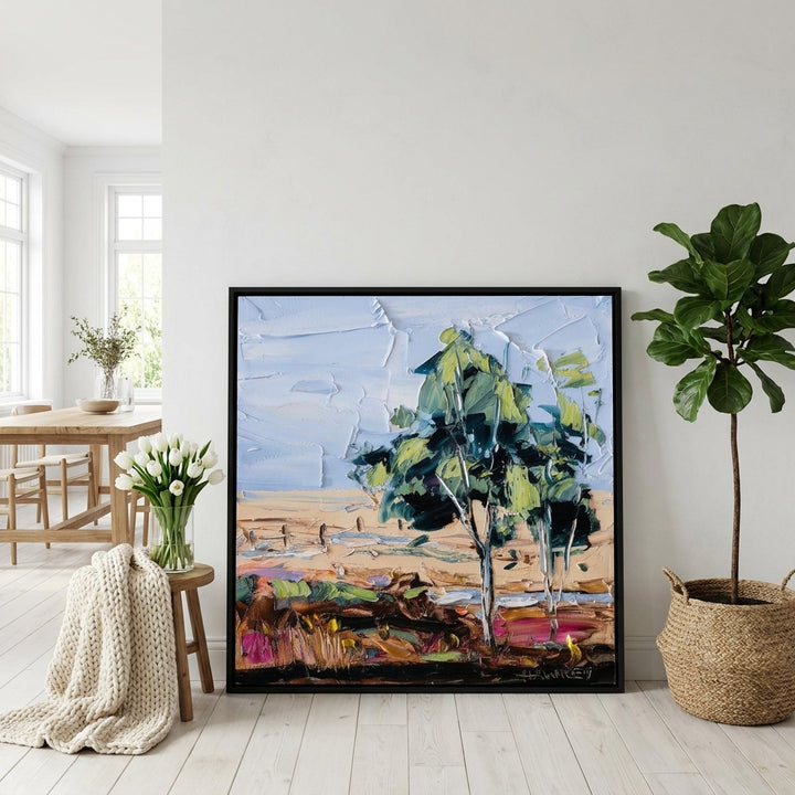 Oversized statement canvas wall art with a black surround leaning against the wall in a bright Scandinavian dining room