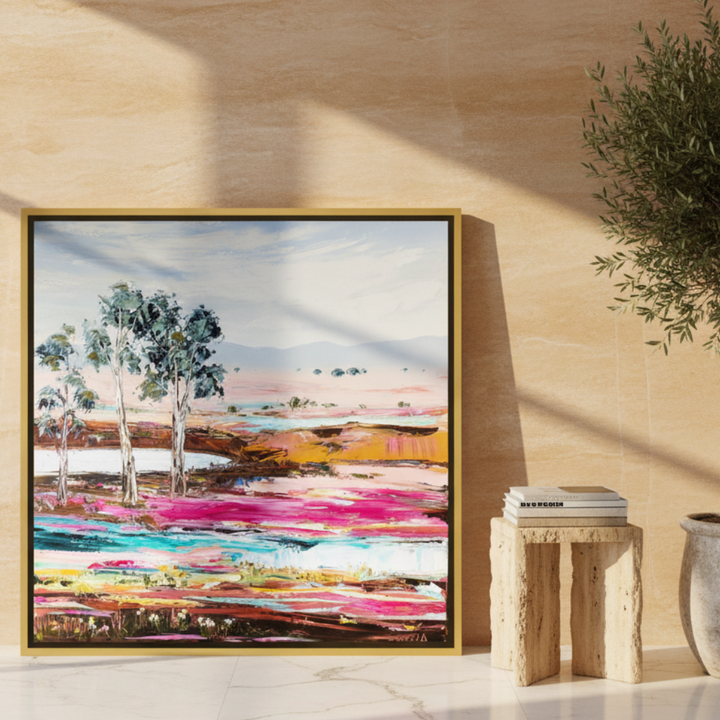 Oversized statement canvas wall art with a gold leaf surround leaning against the wall in a luxe bedroom