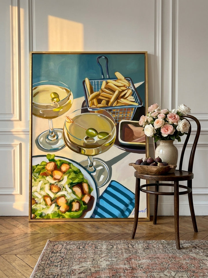 Oversized statement canvas wall art with a gold leaf surround leaning against the wall in a Parisian living room
