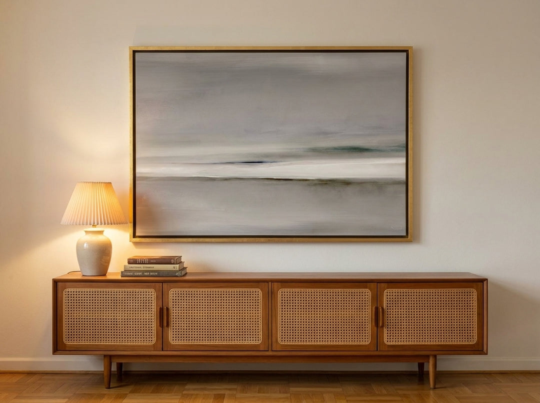 Oversized statement canvas wall art with a gold leaf surround styled on the wall in a mid-century living room