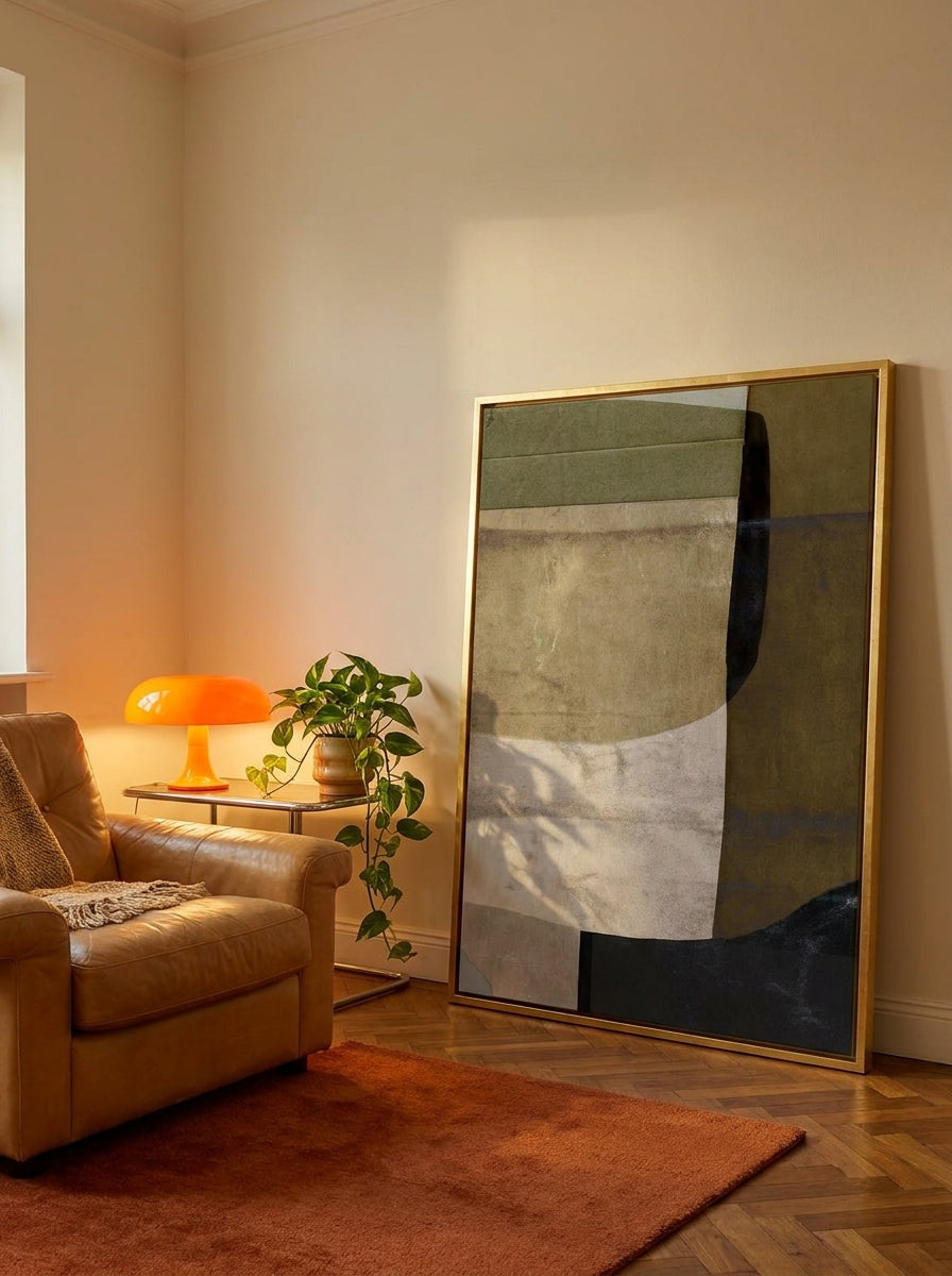 Oversized statement canvas wall art with a gold leaf surround leaning against the wall in a retro 70s living room
