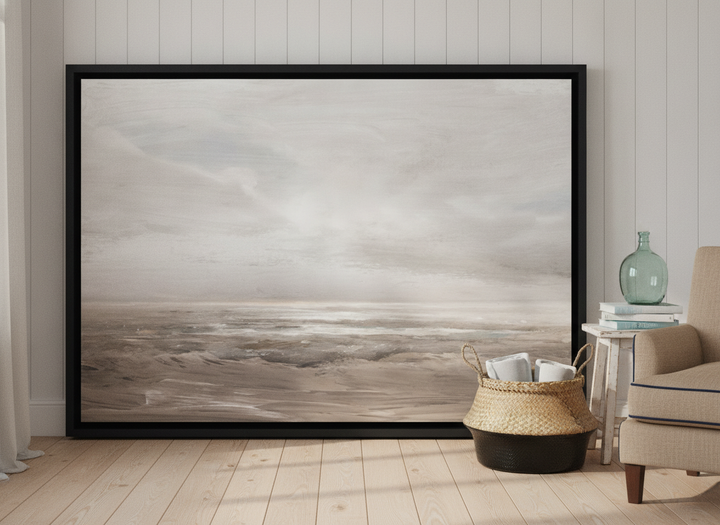 Oversized statement canvas wall art with a black surround leaning against the wall in a coastal bedroom