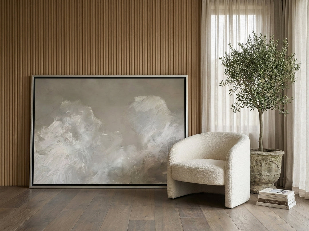 Oversized statement canvas wall art with a silver leaf surround leaning against the wall in a luxe bedroom