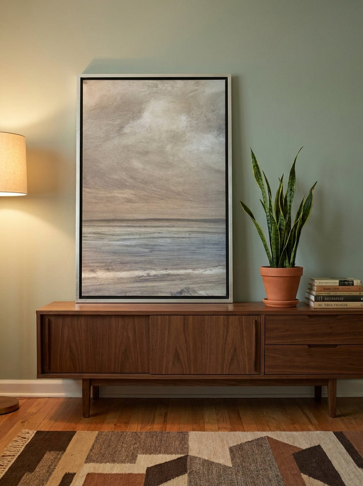 Canvas wall art with a silver leaf surround standing on a sideboard in a mid-century bedroom