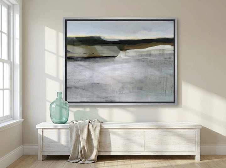Oversized statement canvas wall art with a silver leaf surround styled on the wall in a coastal living room