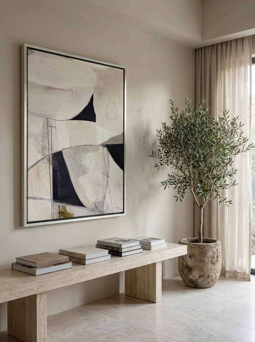 Oversized statement canvas wall art with a silver leaf surround styled on the wall in a luxe living room