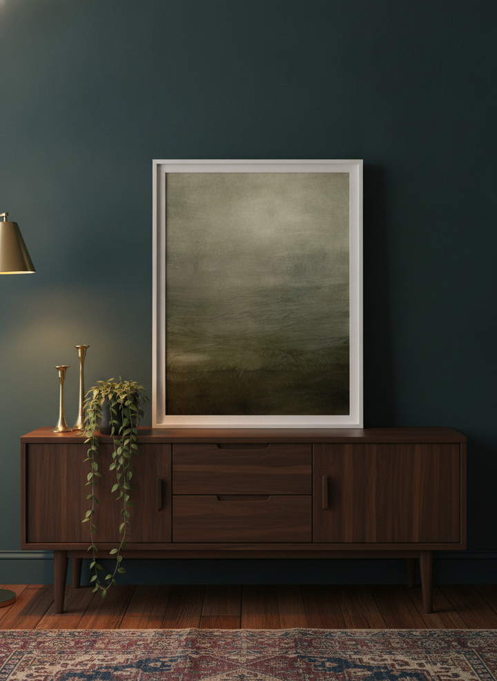 Modern wall art print standing on a sideboard in a moody home office