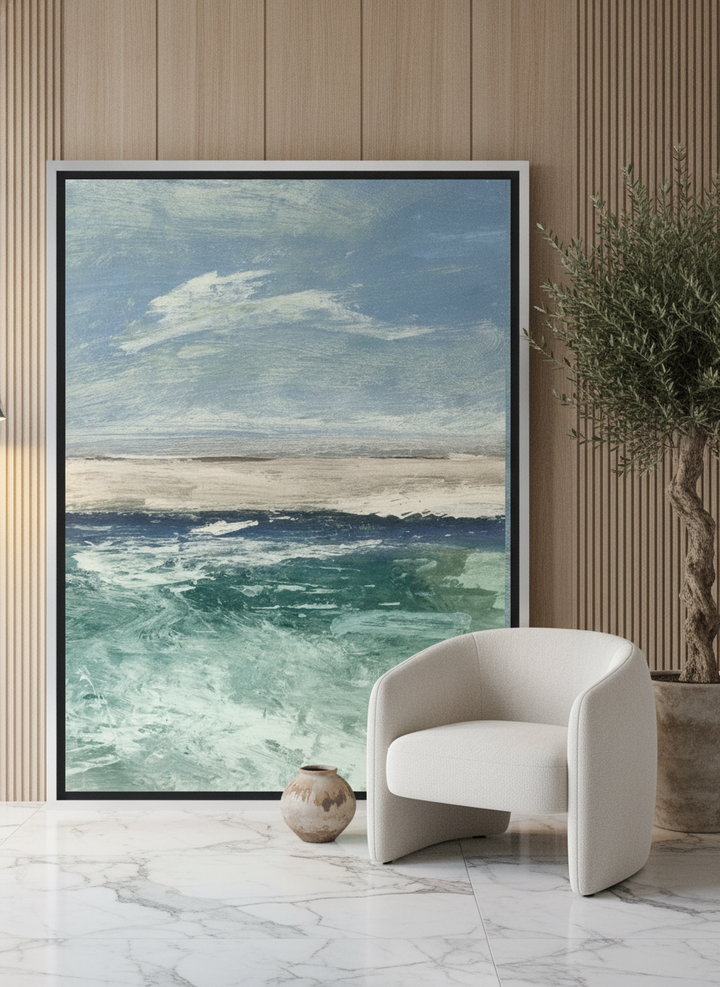 Oversized statement canvas wall art with a silver leaf surround leaning against the wall in a luxe living room