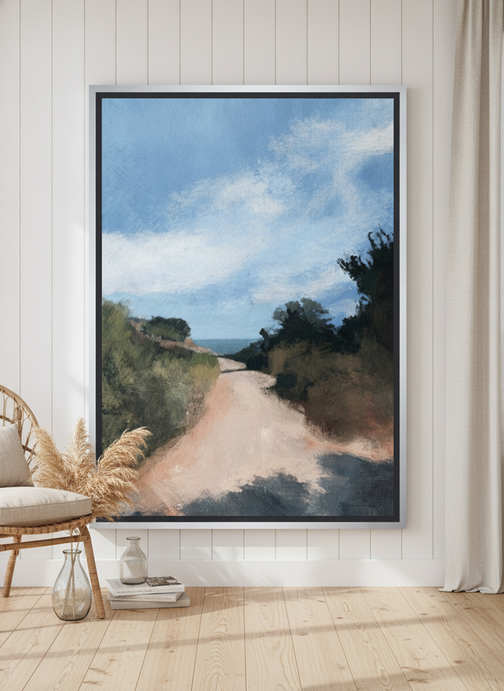 Oversized statement canvas wall art with a silver leaf surround leaning against the wall in a coastal dining room