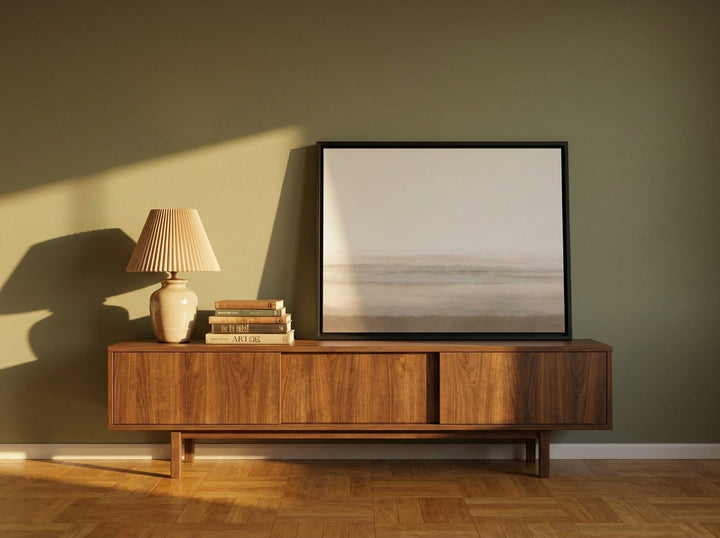 Canvas wall art with a black surround standing on a sideboard in a mid-century living room
