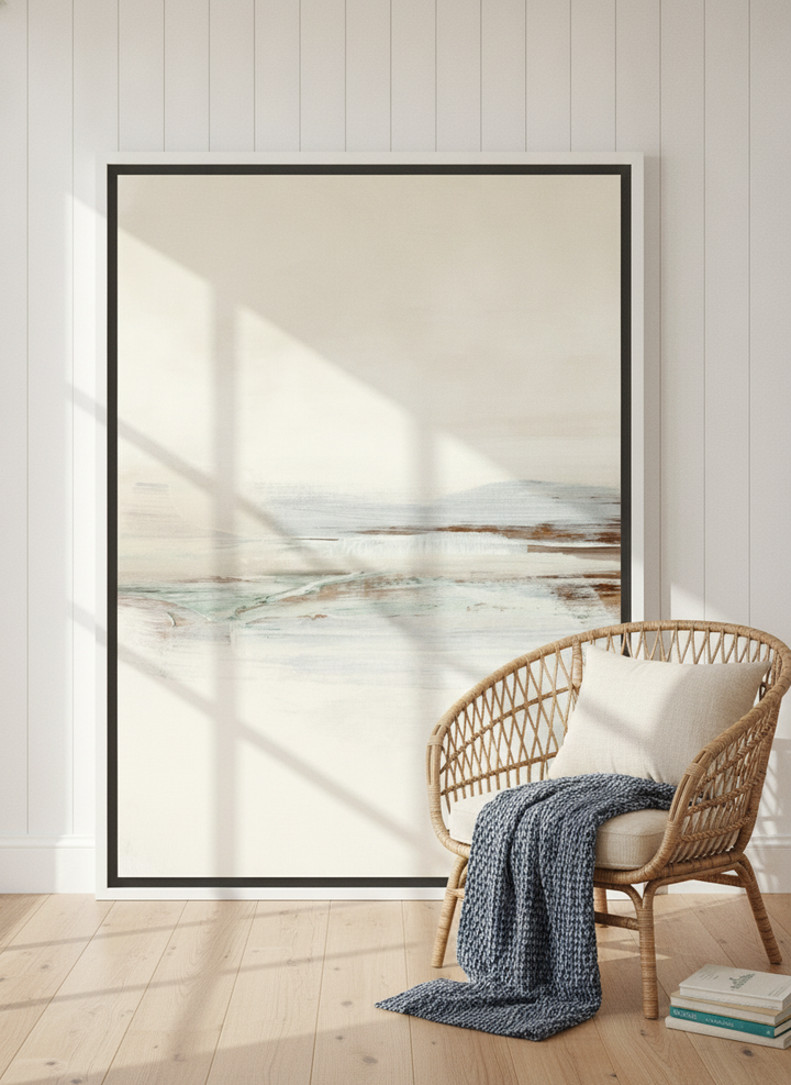 Oversized statement canvas wall art with a white surround leaning against the wall in a coastal living room