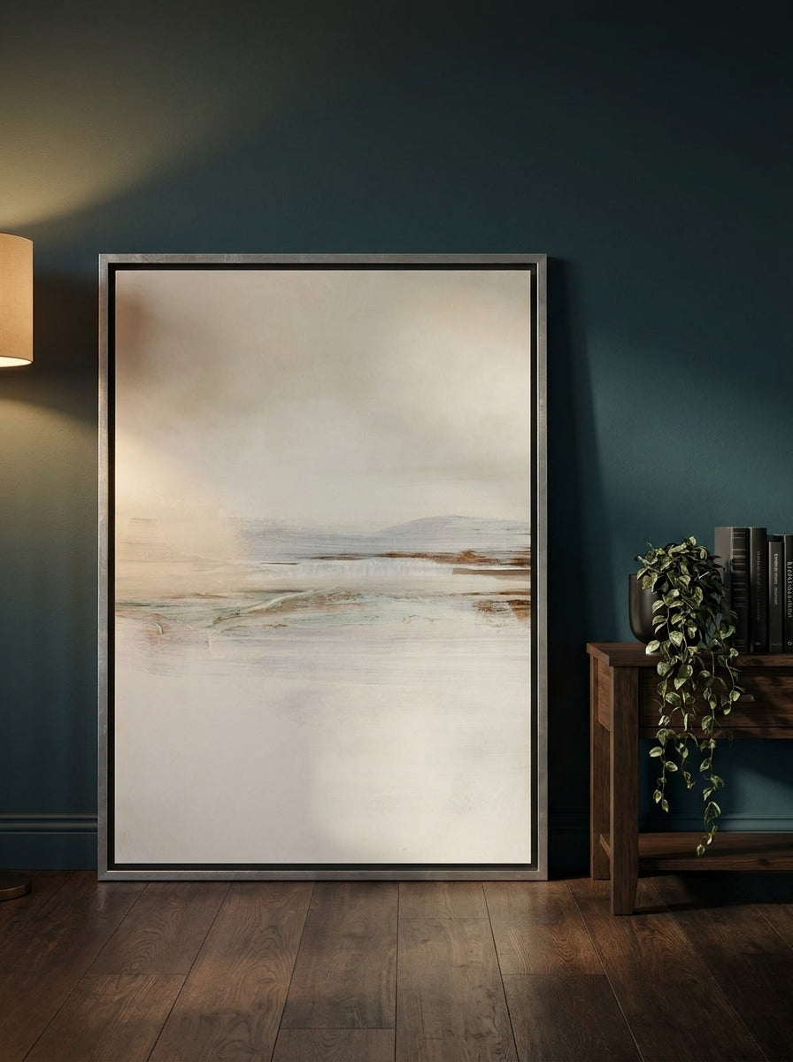 Oversized statement canvas wall art with a silver leaf surround leaning against the wall in a moody living room