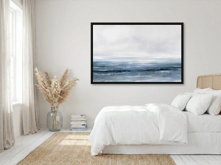Oversized statement canvas wall art with a black surround styled on the wall in a coastal bedroom