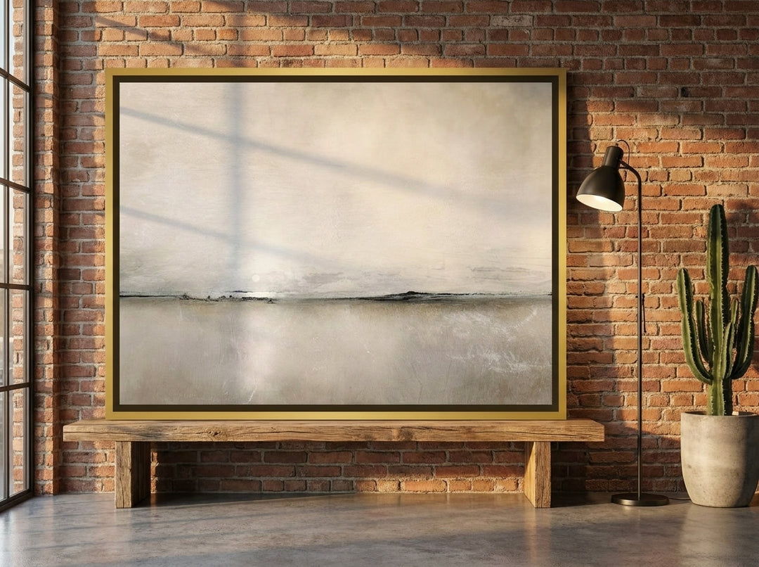 Canvas wall art with a gold leaf surround standing on a bench in an industrial loft home office