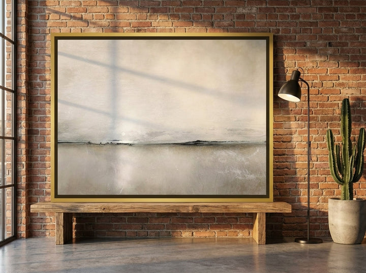 Canvas wall art with a gold leaf surround standing on a bench in an industrial loft home office