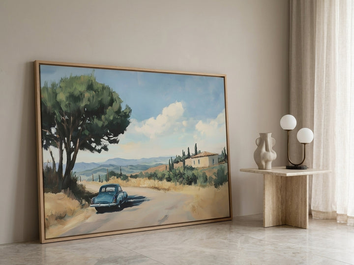 Oversized statement canvas wall art with a natural timber surround leaning against the wall in a luxe living room