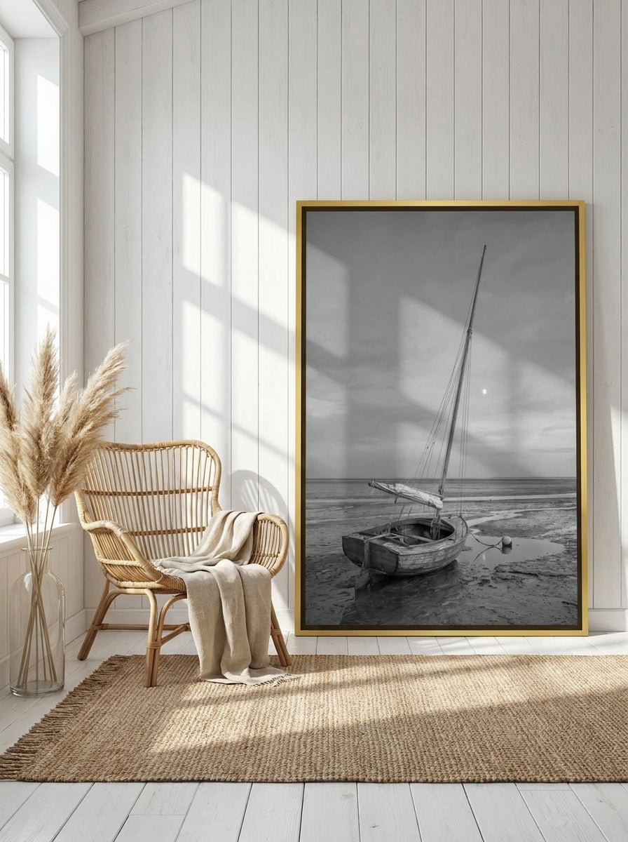 Oversized statement canvas wall art with a gold leaf surround leaning against the wall in a coastal living room