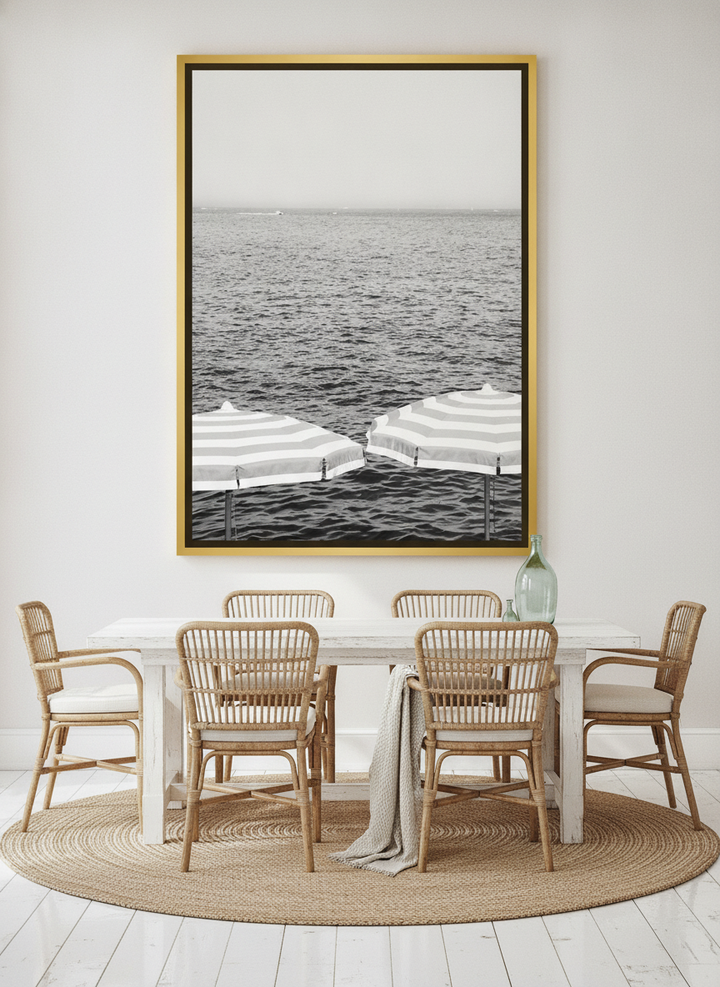 Oversized statement canvas wall art with a gold leaf surround styled on the wall in a coastal dining room