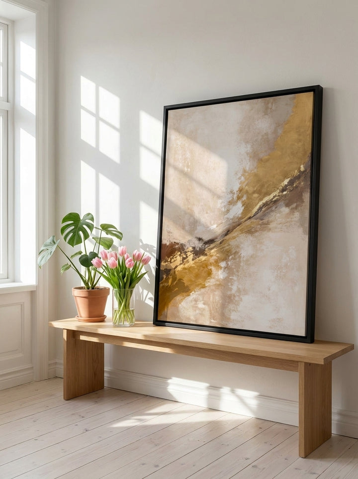 Canvas wall art with a black surround standing on a bench in a bright Scandinavian home office