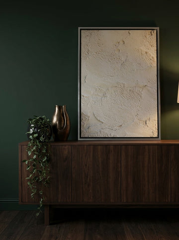 Canvas wall art with a silver leaf surround standing on a sideboard in a moody home office