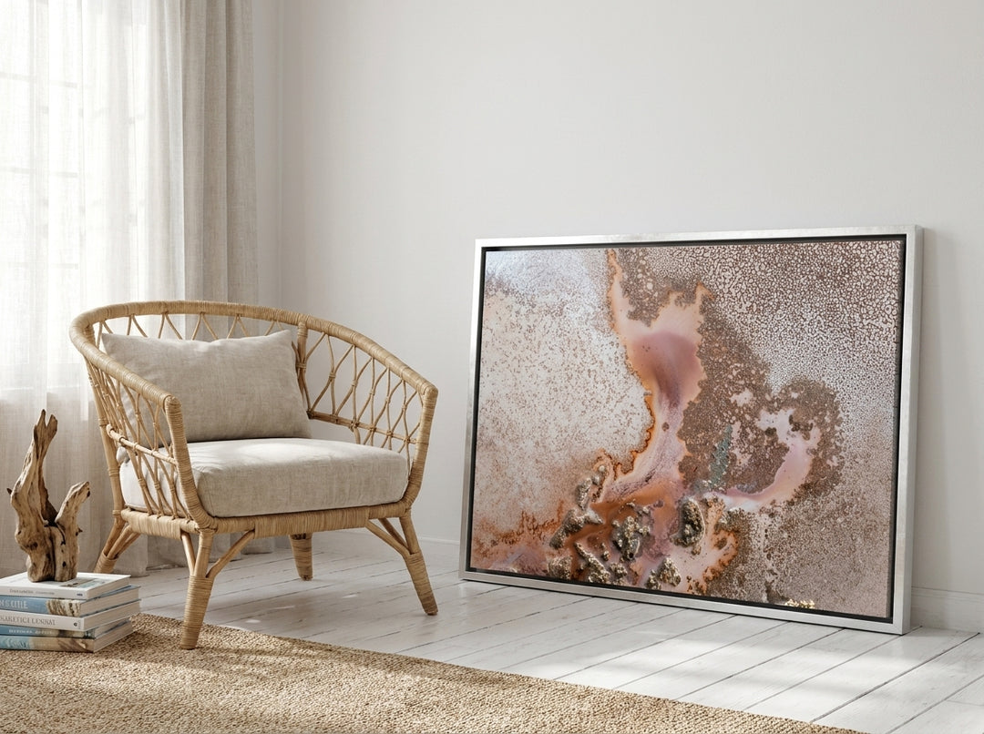 Canvas wall art with a silver leaf surround leaning against the wall in a coastal bedroom