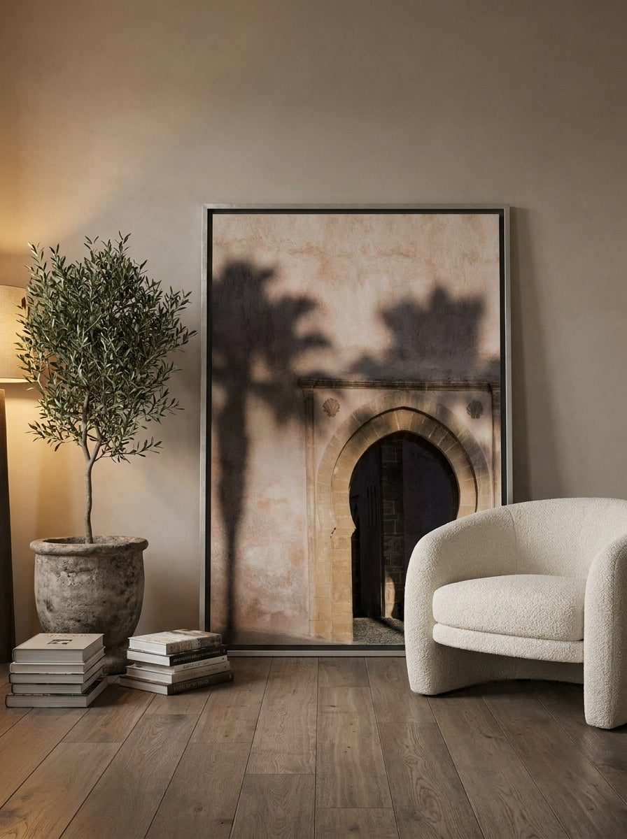 Oversized statement canvas wall art with a silver leaf surround leaning against the wall in a luxe bedroom