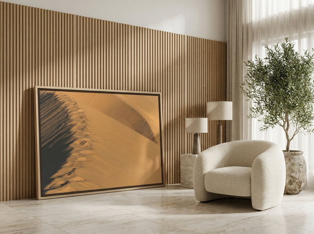 Oversized statement canvas wall art with a natural timber surround leaning against the wall in a luxe living room