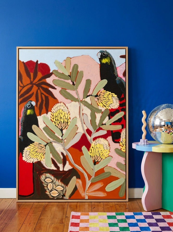 Oversized statement canvas wall art with a natural timber surround leaning against the wall in a colourful eclectic dining room