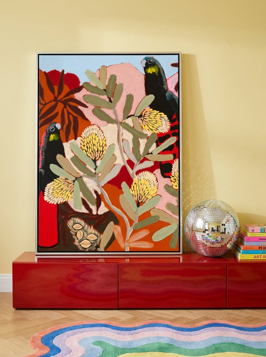 Canvas wall art with a silver leaf surround standing on a sideboard in a colourful eclectic bedroom