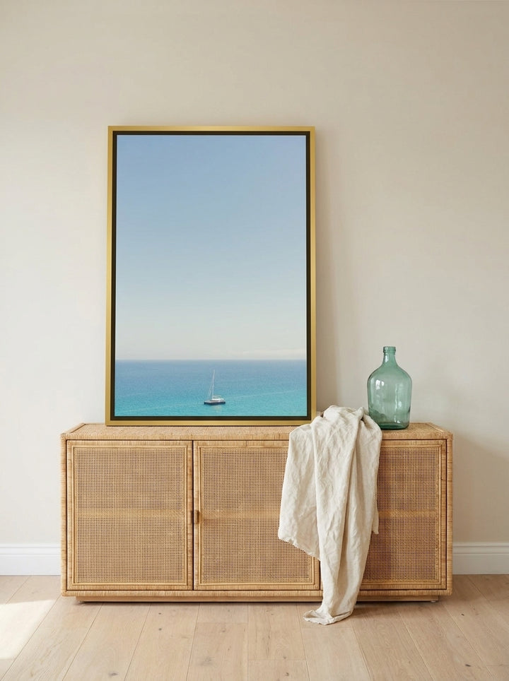 Canvas wall art with a gold leaf surround standing on a sideboard in a coastal bedroom