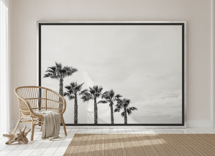 Oversized statement canvas wall art with a silver leaf surround leaning against the wall in a coastal dining room