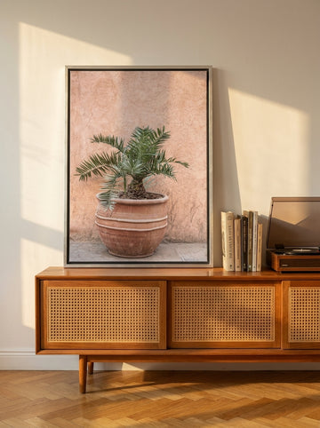 Canvas wall art with a silver leaf surround standing on a sideboard in a mid-century bedroom