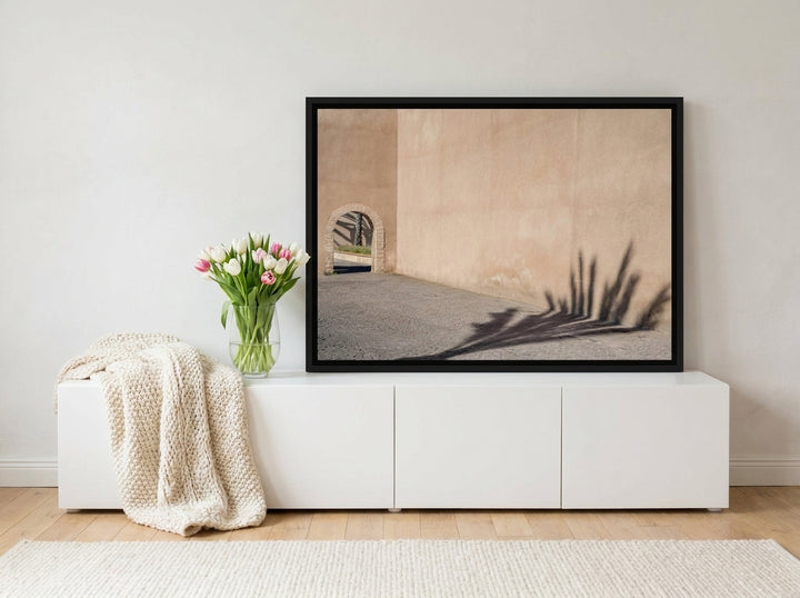 Canvas wall art with a black surround standing on a sideboard in a bright Scandinavian living room
