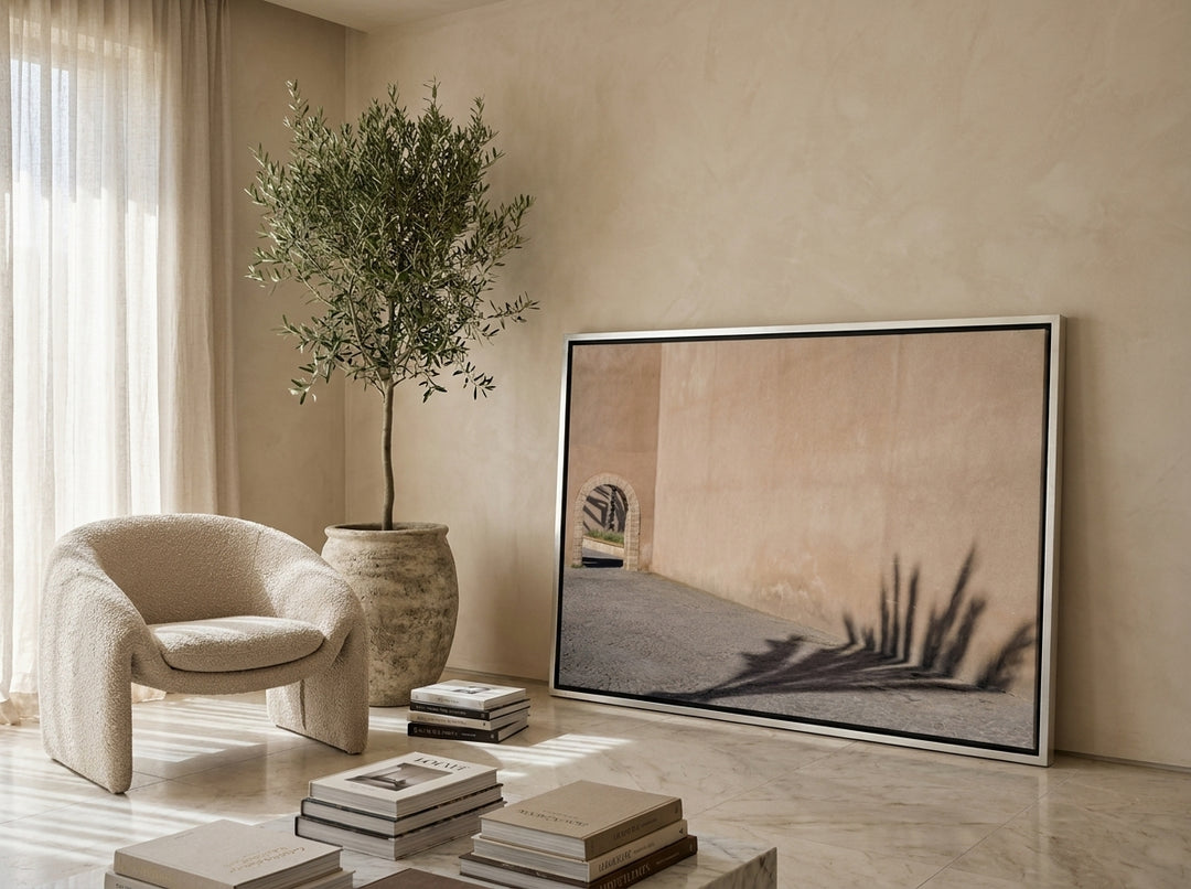Oversized statement canvas wall art with a silver leaf surround leaning against the wall in a luxe living room