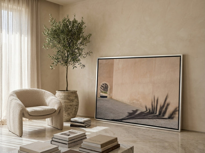 Oversized statement canvas wall art with a silver leaf surround leaning against the wall in a luxe living room