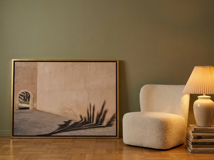 Canvas wall art with a gold leaf surround leaning against the wall in a mid-century home office