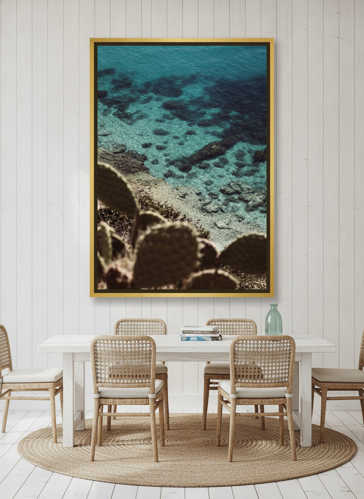 Oversized statement canvas wall art with a gold leaf surround styled on the wall in a coastal dining room
