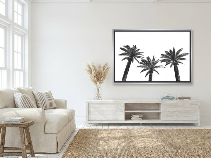 Oversized statement canvas wall art with a silver leaf surround styled on the wall in a coastal living room