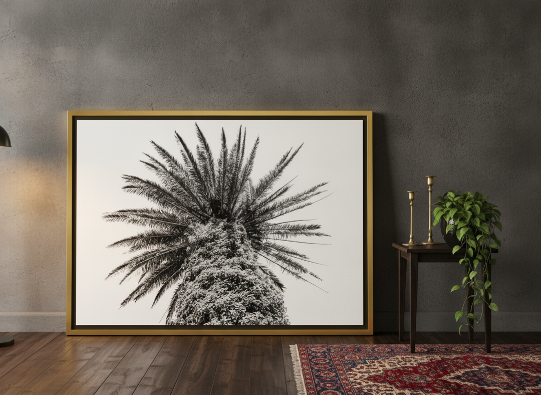Oversized statement canvas wall art with a gold leaf surround leaning against the wall in a moody living room
